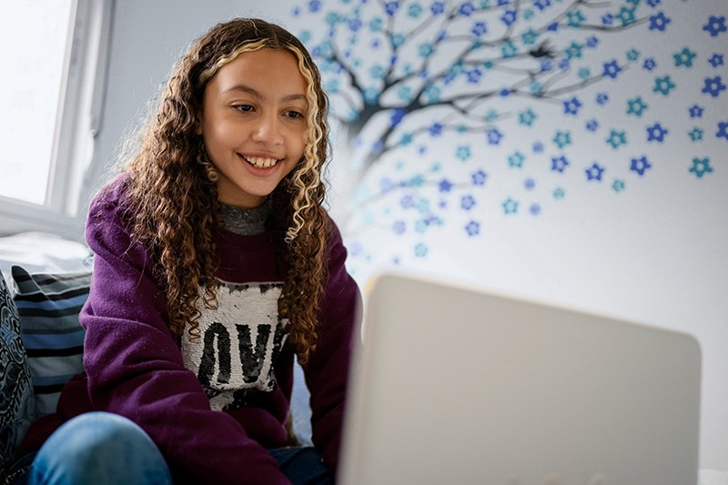 Middle school student sitting and typing on laptop